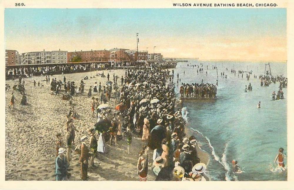 POSTCARD - CHICAGO - WILSON AVENUE BATHING BEACH - HUGE CROWD MOSTLY STANDING DRESSED BY WATER - NOTE LONG STTING PAVILION LEFT BACKGROUND - TINTED - 1915