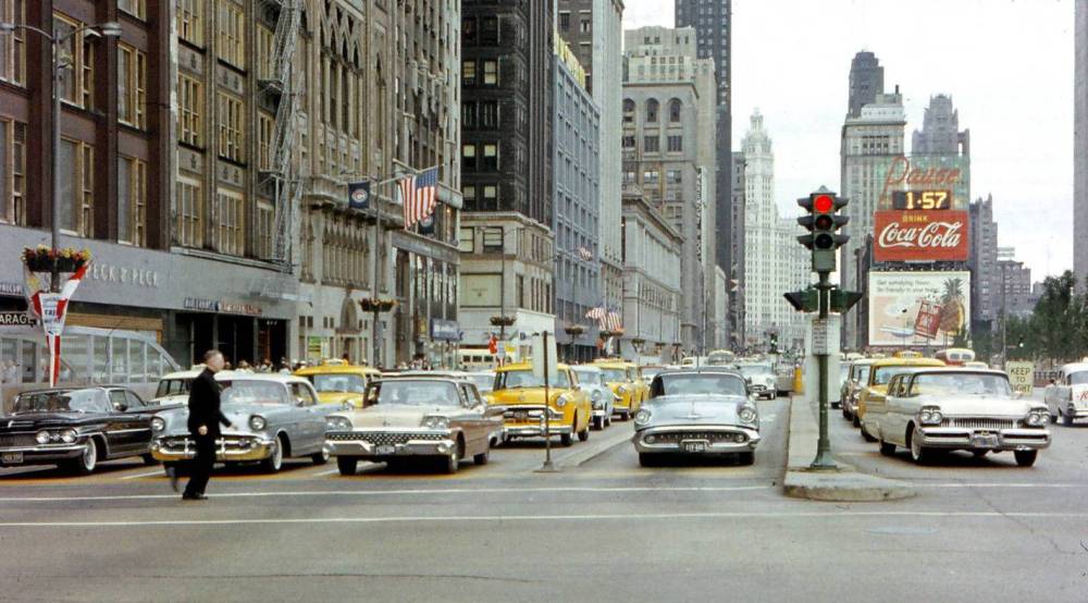 A PHOTO - CHICAGO - MICHIGAN AVE - LOOKING N GROUND LEVEL FROM NEAR UNDERGROUND PARKING EXIT - MAN CROSSING STREET - HEAVY TRAFFIC - YELLOW CABS - c1960