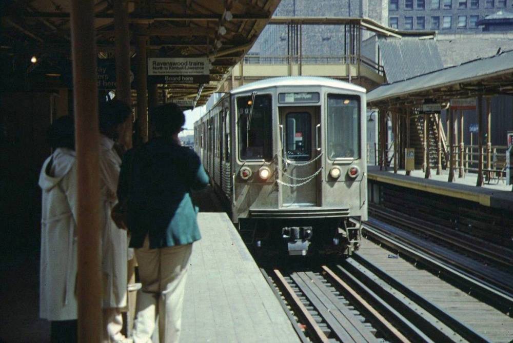 A PHOTO - CHICAGO - CTA ELEVATED RAPID TRANSIT - 2200 SERIES TRAIN COMING INTO UNKNOWN STATION - PEOPLE WAITING - 1979