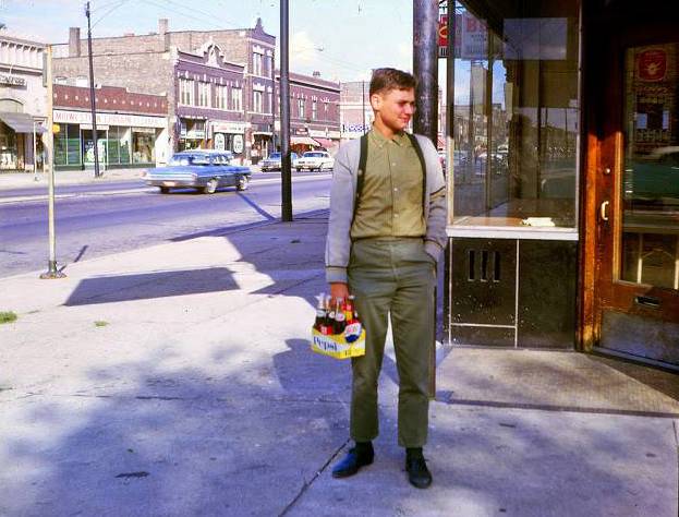 a photo - chicago - unknown neighborhood shopping street - young man standing with a carton of pop - edited from site everyday life of chicago in the 1960s